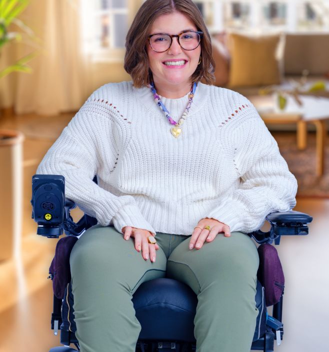 A young woman with FA smiles while sitting in her wheelchair.