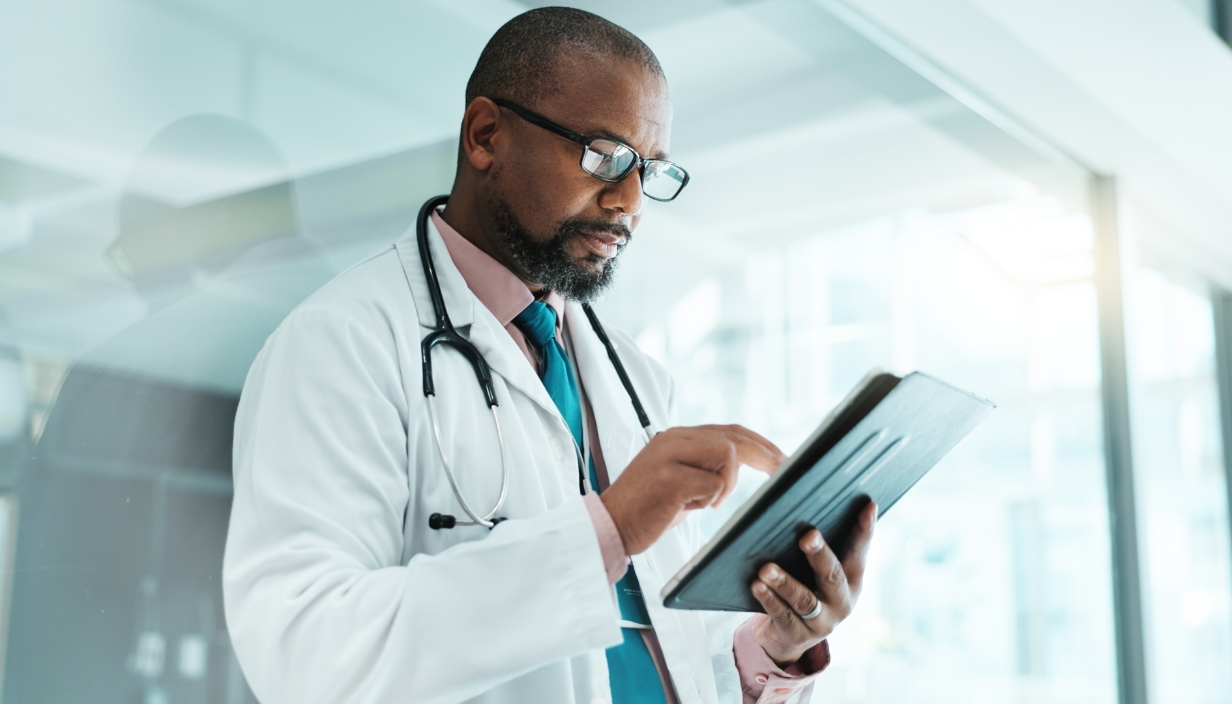 A male doctor reviewing documents on a tablet.